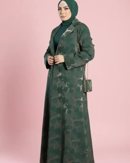 موديل ترتدي عباية بليزر من قماش الجاكار الفاخر بنقوش ذهبية تظهر إطلالة كاملة مع الفستان البيزك والحزام من متجر زيلينا.